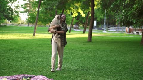 The girl and pug dog are having fun, she throws the dog in the air in the park