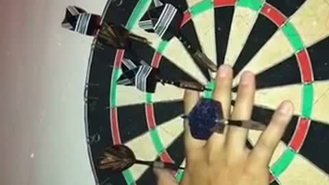Slowmotion dart barely misses finger on board at night