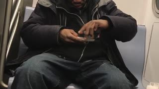 Man rolls cigarette while sitting on subway