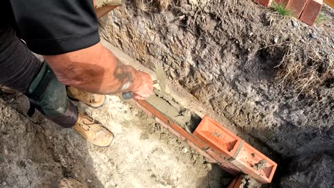 OLD BOY laying a brick in the footings!