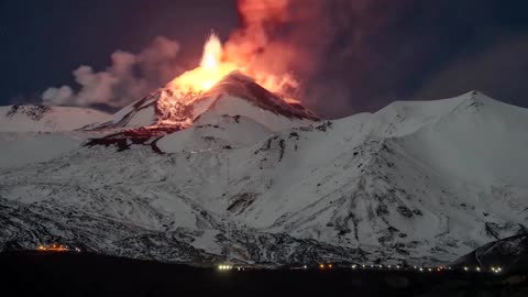 Snowy Mount Etna spurts lava into night sky