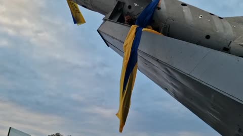 A man flies a Ukrainian flag from a Soviet-era plane on a pedestal in Bakhmut