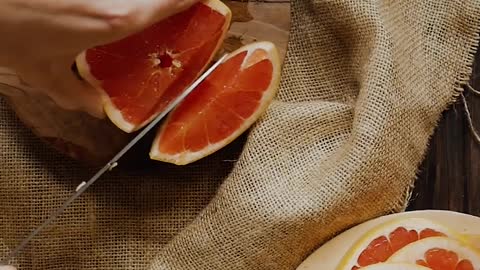 A Person Cutting a Grapefruit into Slices by Using a Knife