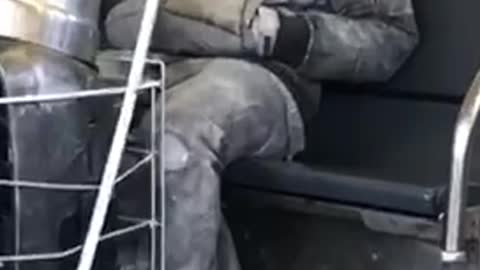 Silver body spray paint man sits with sunglasses in subway