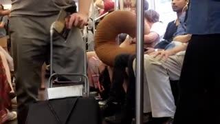 Guy pushing speaker playing trumpet subway