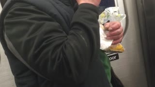 Drunk man black jacket struggle to eat sandwich