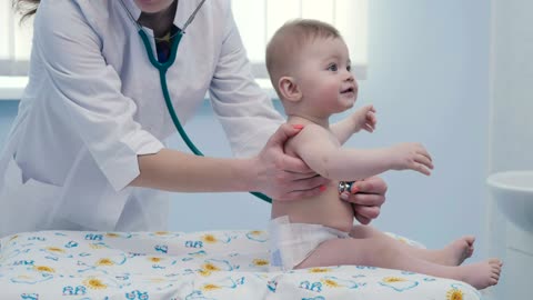 Cute baby reaction when female doctor listening to him with a stethoscope