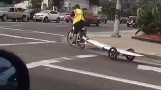 Guy on bike with his surf board behind him
