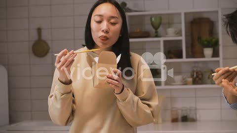 Happy Japanese Woman Holding Chopsticks While Eating Ramen In The Kitchen