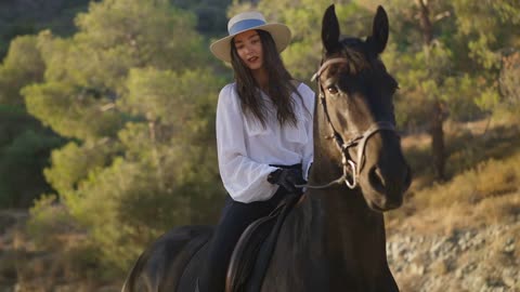 Beautiful young equestrian smiling looking at camera sitting on back of purebred horse