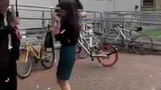 Girl holding champagne bottle gets startled by cork that hits umbrella