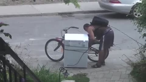 Guy attempts to move massive chest freezer strapped to bicycle