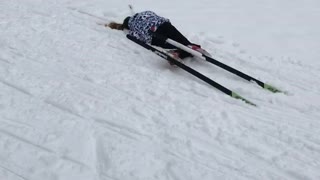 Girl trying to run in skis falls forward into snow