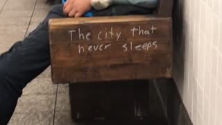 A man in a blue jacket asleep on bench