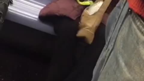 Woman purple puffy jacket peeling fruit on subway train with knife