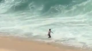 Guy walks into ocean slammed by wave