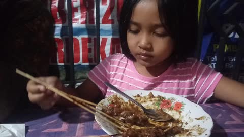 Little Girl Like to Eating satay with peanut sauce