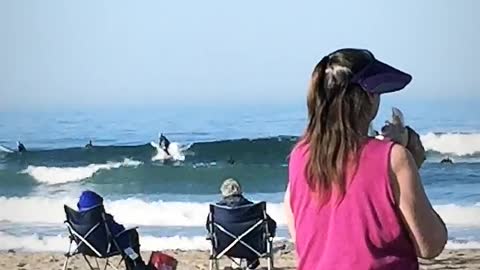 Pink shirt woman blows conch shell on beach