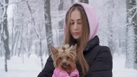 lonely cute girl with long hair hugging a yorkshire terrier dressed in wool sweater holding dog