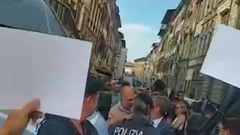 Polizisten in Italien sind von älteren Menschen umgeben, die Bilder von Impfopfern hochhalten