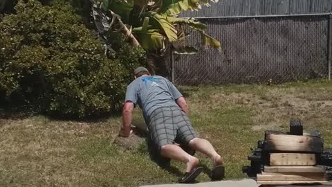 Man belly surfs on grass backyard