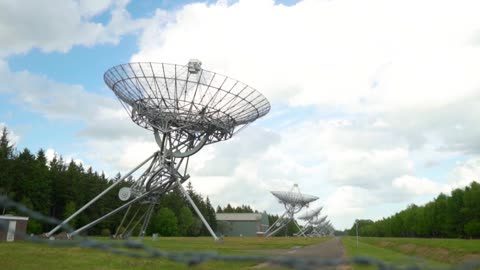 Large satellite dishes lined up in a meadow