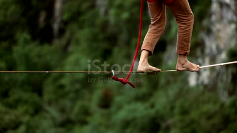 Man traverses highline stretched above waterfall, valley