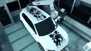 A robot paints art on a car