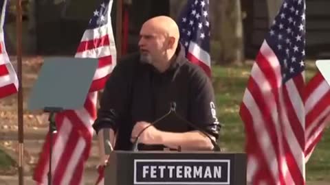 John Fetterneck says he’s standing on the stage with a president that is sedition free and all the flags are blown down behind him