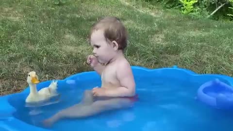 Baby and duckling are swimming together.