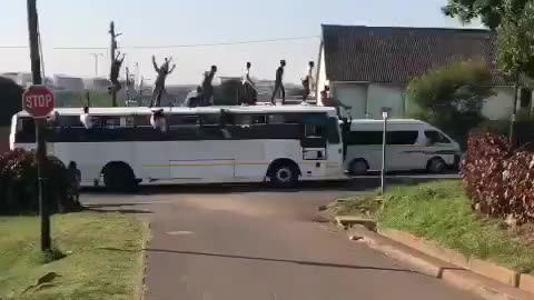 Group of youths ride on top of a moving bus in Durban