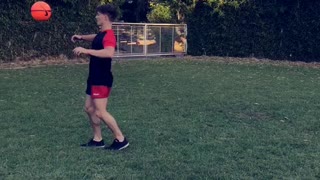 Kid in red and black kicks ball lands on back neck