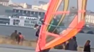 Guy skateboarding with an orange wind surfing kite