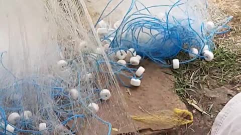 A fisherman weaving his fishing net