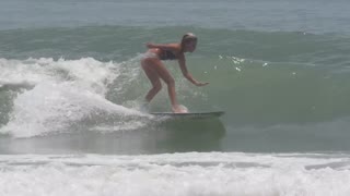 Woman black and white bathing suit falls on back while surfing