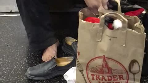 Man with shoes white socks off trader joes bag