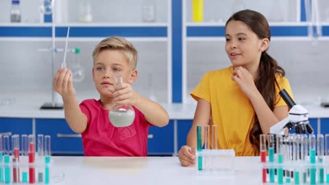 Selective focus of children adding blue liquid in water