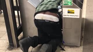 Drunk guy kneeling on floor at subway turnstile