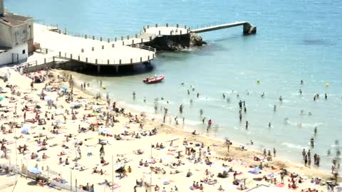 Beach full of tourists next to the pier