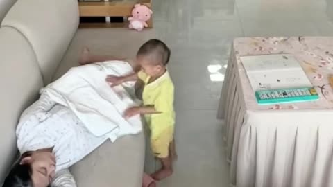 Toddler covers pregnant mother with blanket as she falls asleep