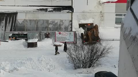 The tractor cleans the road from snow.