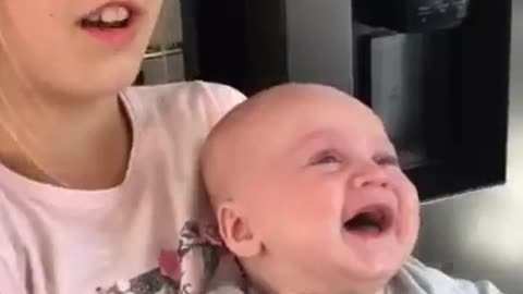 baby is laughing hysterically at a tea towel being waved in the air