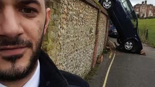 Man Bewildered by Car Blowing over Rock Wall