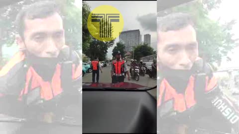 Un inspector de transportes en Yakarta subido al capó de un VTC en marcha