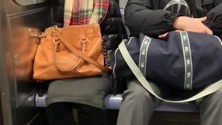 Woman wearing plaid scarf on a subway sleeping and flailing her hands up and down