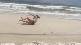 Girl running in sand jumps and falls down