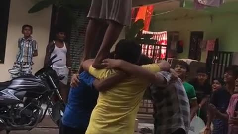 Kids banding together to lift friend in pink shirt to take down and break pinata