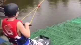 Boy kneeling on red ski pulled by rope