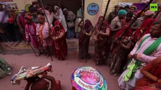 Indian women beat men with wooden sticks at Lathmar Holi festival