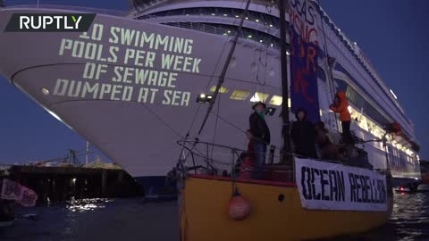 XR projects a strongly worded message onto a cruise ship in a flotilla protest